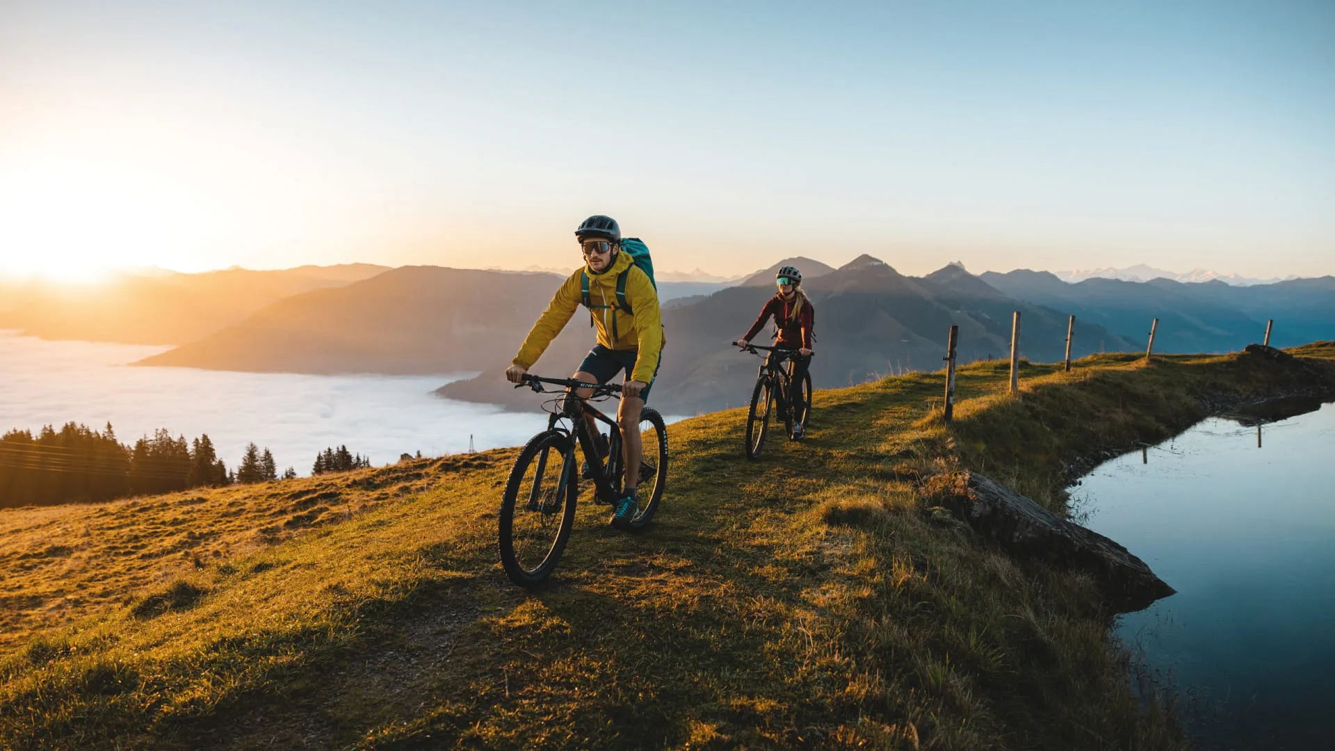 Mountainbiker fahren im Brixental bei Sonnenuntergang entlang einem Weg.