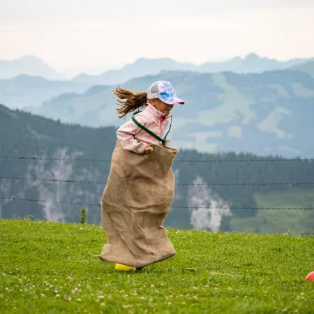 Mädchen springt in einem Sack auf einer Wiese in den Alpen