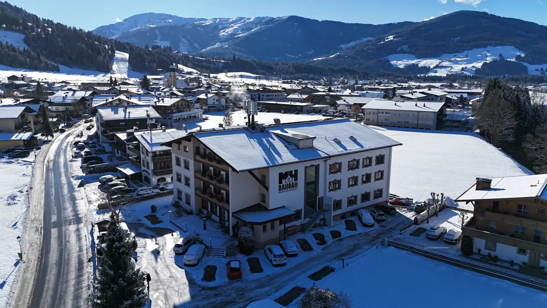 Blick auf ein schneebedecktes Dorf mit Bergen im Hintergrund