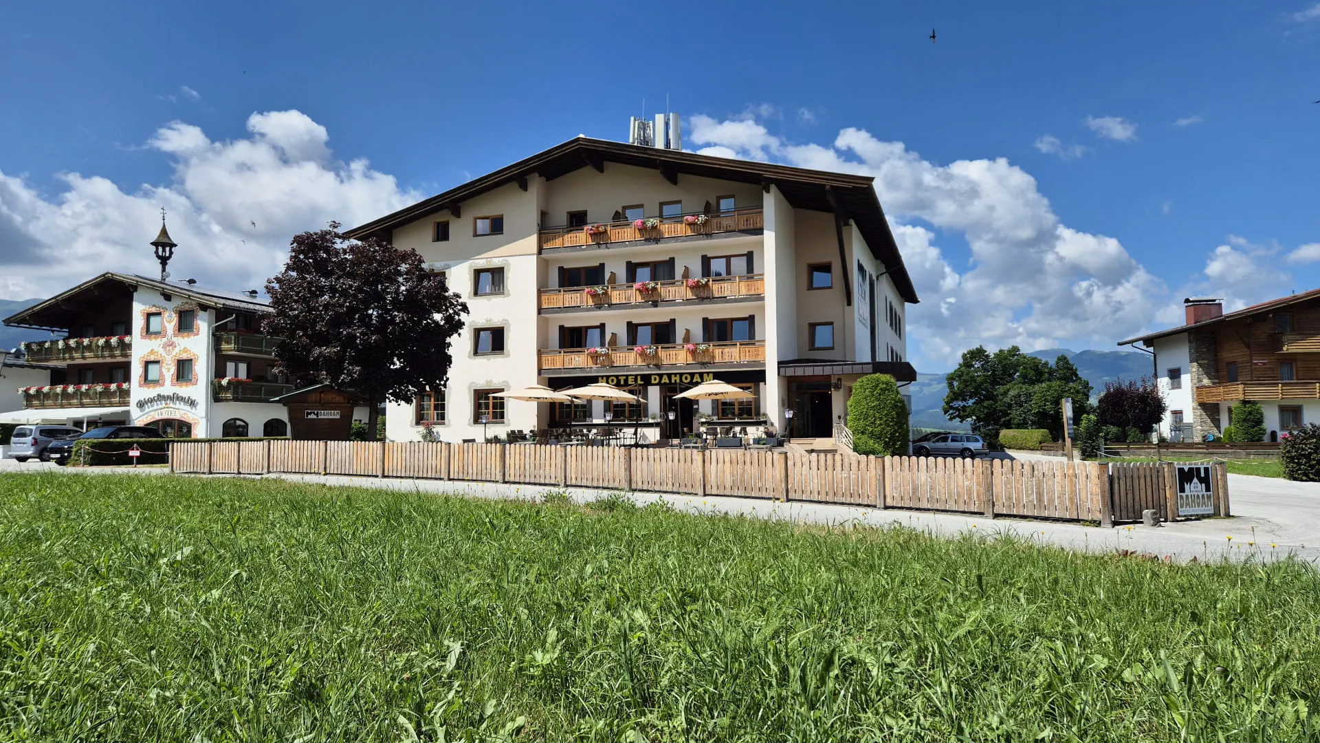 Sommeransicht eines Hauses mit Balkonen und Garten.