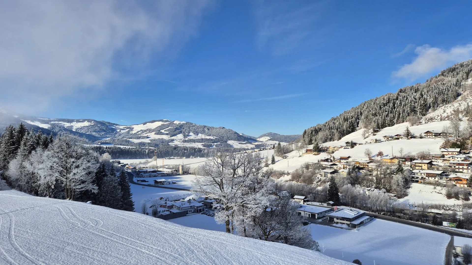 Schneebedeckter Ausblick auf ein Tal mit Bergen und einem klaren blauen Himmel