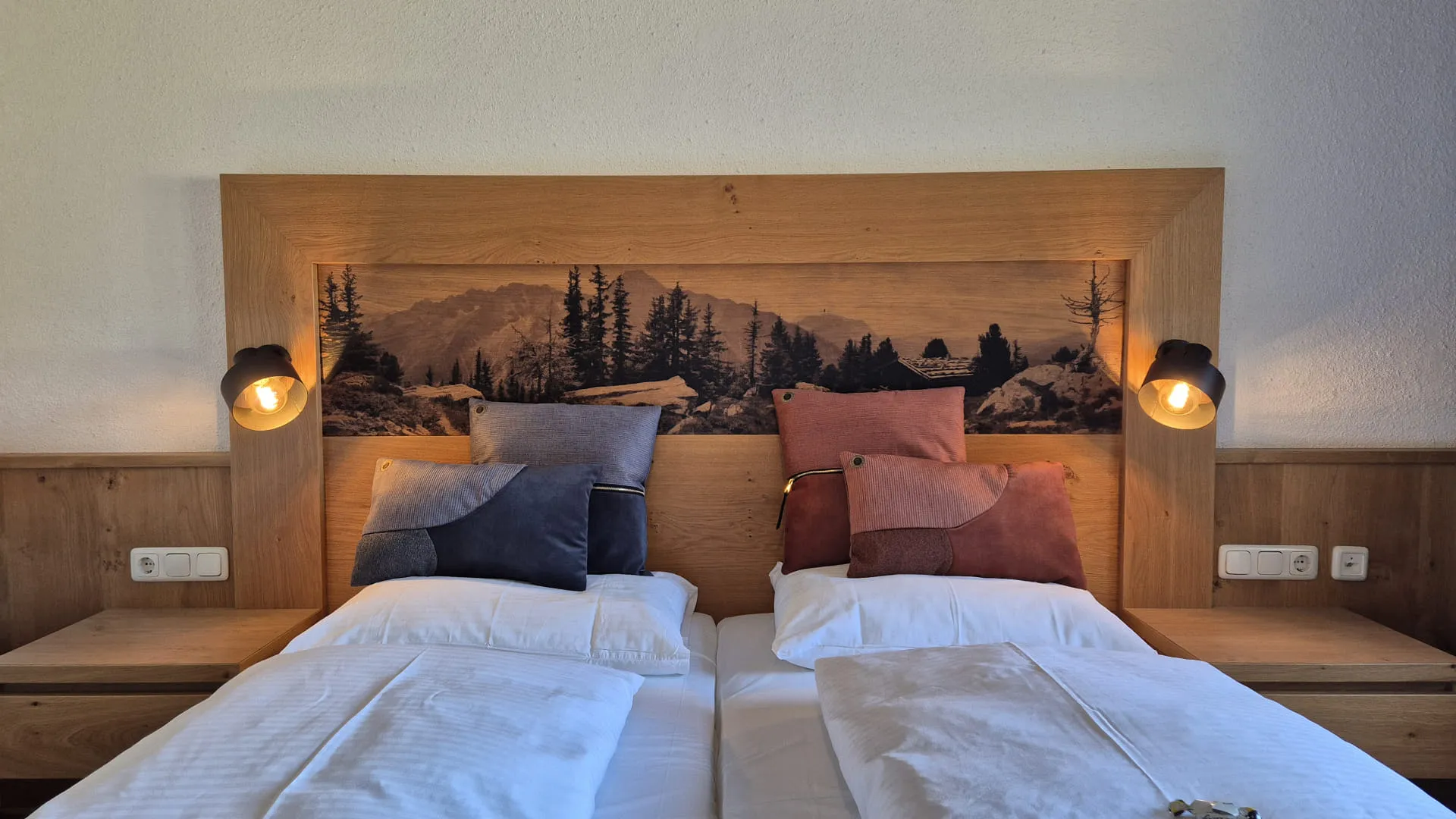 Zweibettzimmer mit Holzoptik und Landschaftsbild im Hintergrund