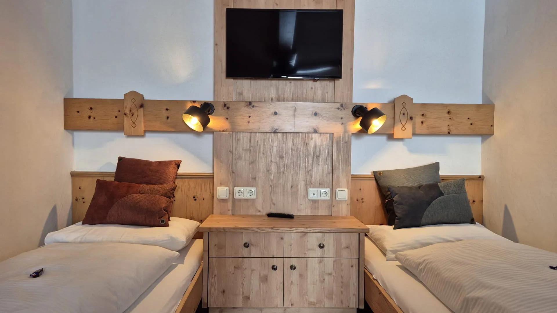 Kamer mit zwei Einzelbetten, Fernseher und Holzmöbeln