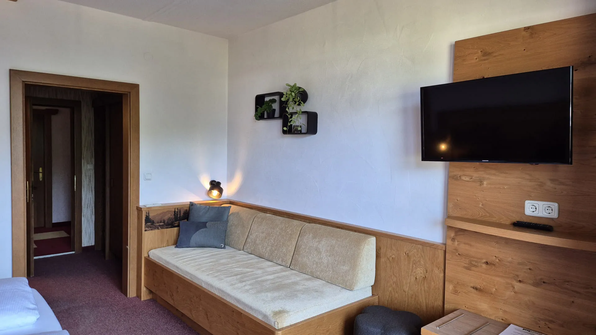 Helles Zimmer mit Sofa, TV und Zugang zu einer Tür